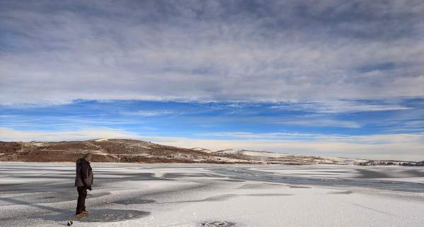 A fisherman stands on ice at Panguitch Lake in Utah.