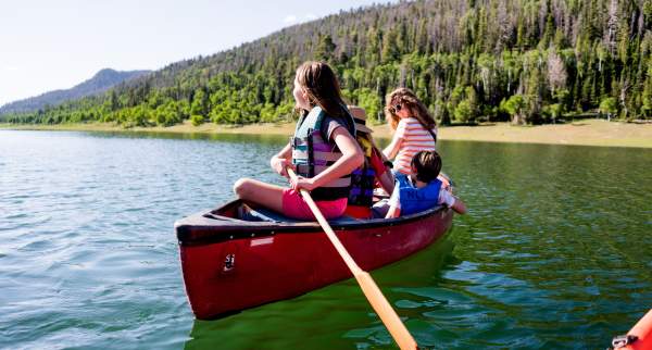 Family in a red canoe on the water of Navajo Lake, Utah.