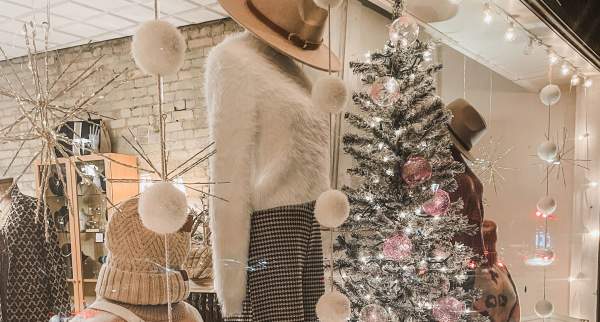 a clothing storefront with holiday decorations and a christmas tree with lights.