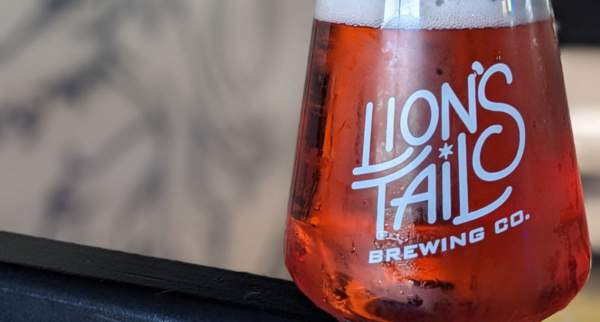 Glass of amber beer bearing the Lion’s Tail Brewing Co. logo.