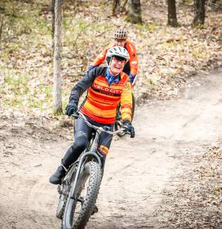 two peddal bikers riding on trail in woods