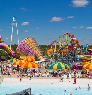 photo of water park, pool with multi color umbrellas and rides in background