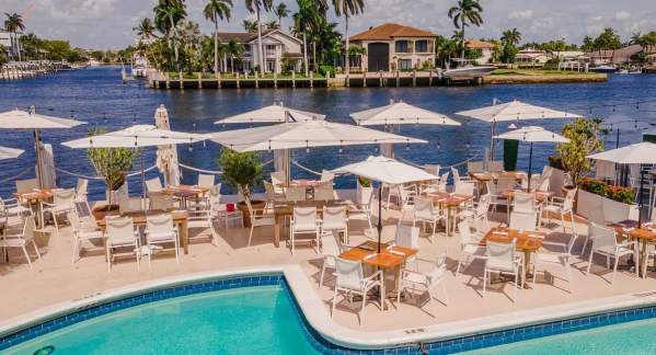 the view from the back of Sands Harbor Resort & Marina that shows part of the pool, several tables with umbrellas and the Intracoastal Waterway in the background
