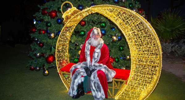 Santa Clause sitting on a bench in a big gold ornament