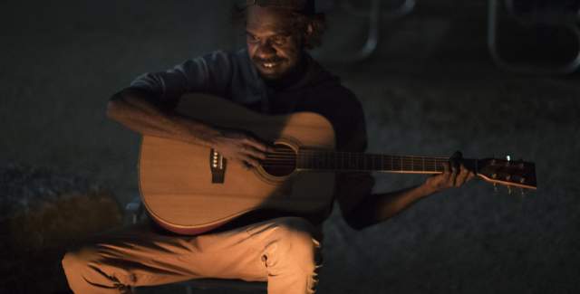 A tour guide from Mimbi Caves Campground sings and plays guitar around the campfire.