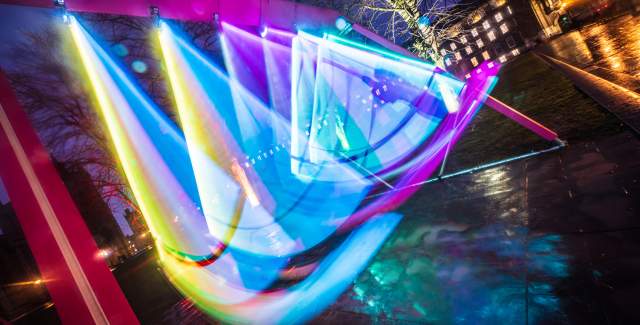 A light installation of a swing set covered in flourescent lights