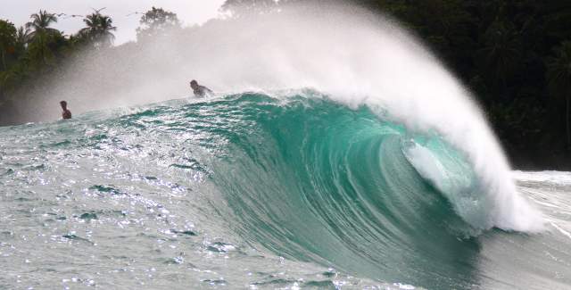 Two surfers riding a beautiful huge wave