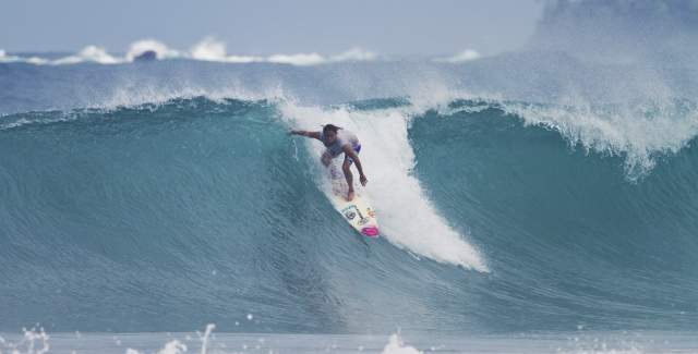 Woman riding a huge wave on a surf board at Bocas del Toro