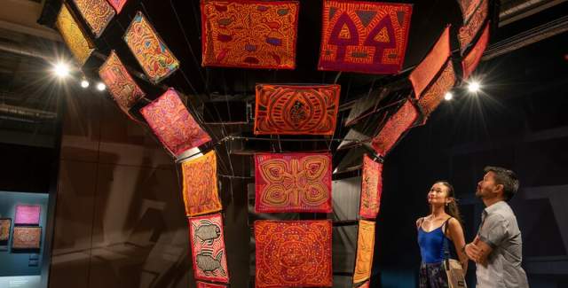 Visitors at Museo de La Mola admire assorted Mola textile collection.