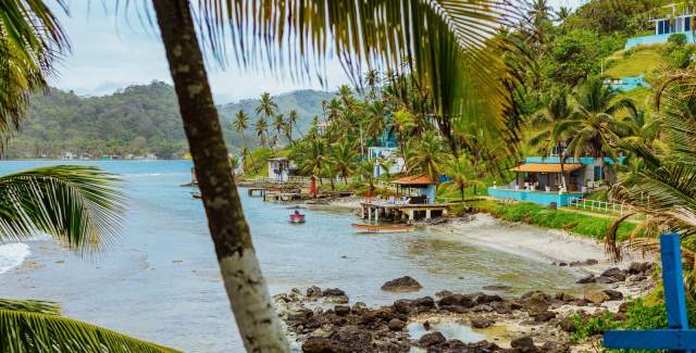 Couple walking near a pool with surfboards, Isla Grande beach can be seen in the background
