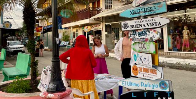 There are many signs pointing in different directions, with various destinations written on them. Some of the visible destinations include "TRANSPARENTE," "YALI-YALI," "BUENA VISTA," "EL REFUGIO," "LIFTY," and "BROTHER'S."