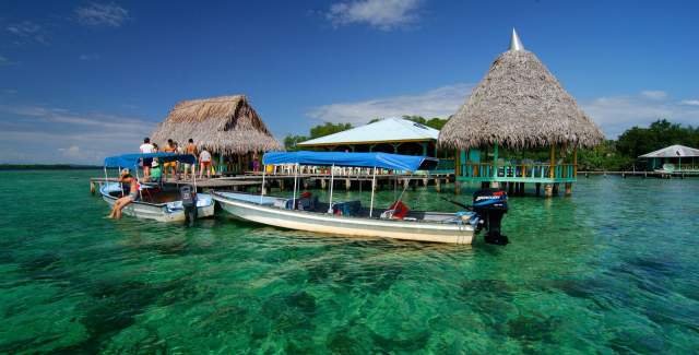 Boat near a palm Hut in Bocas del Toro, in a pristine blue waters