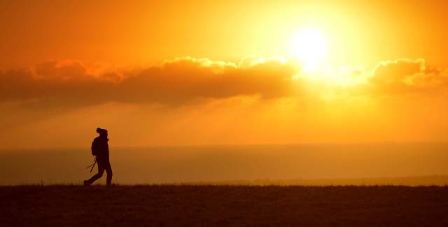 A lone walker on the South Downs in Sussex at sunset