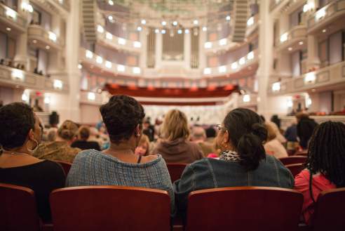 Row of people sitting in spacious Palladium Theater ready for performance to begin