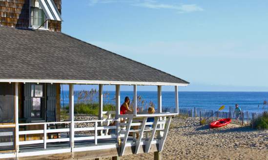 Visitors enjoy the fresh air and view from the wrap-around porch of their Outer Banks vacation rental.