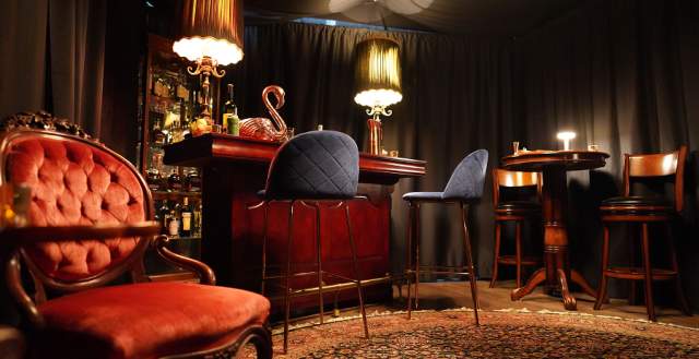 Inside of Room 901, plush velvet chair in front of a mahogany colored private bar.