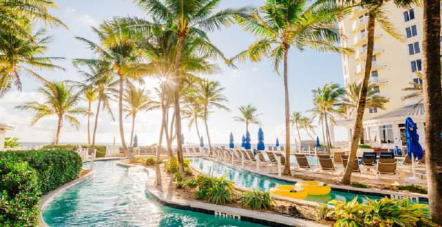 Lazy River at the Pelican Grand Resort on a sunny day with palm trees and a bright blue sky