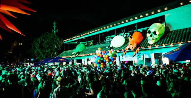 A crowd of people watching an evening Halloween parade