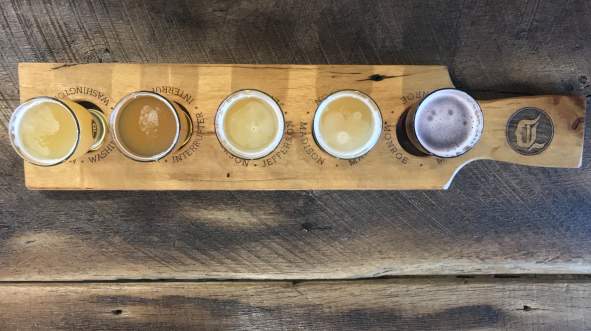 A wooden flight paddle holds five small glasses of craft beer at Dynasty Brewing Co. in Lee.