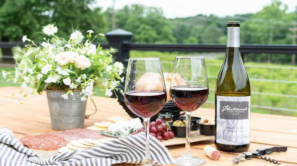 Two glasses of Fleetwood Farm Winery Pinot Noir with a charcuterie spread on an outdoor deck in Leesburg, Virginia