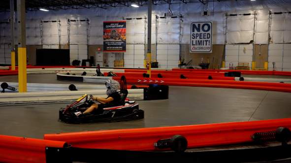 Person racing in a red go-kart on the indoor track at K1 Speed in Sterling, Virginia.