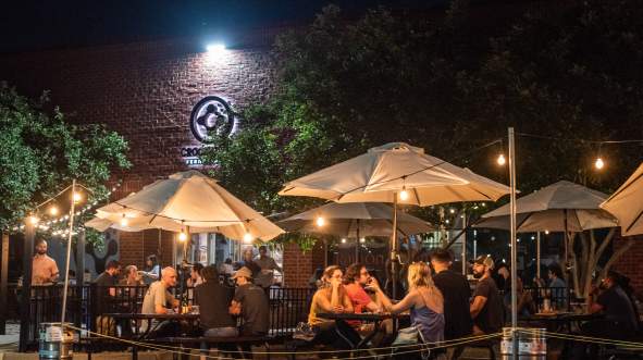 Evening crowd at picnic tables under string lights on the outdoor patio at Crooked Run Fermentation in Sterling