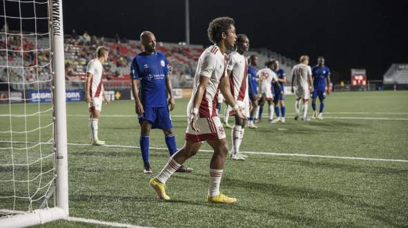 Loudoun United FC and opposing players line up near the goal during a night match at Segra Field in Loudoun County, Virginia