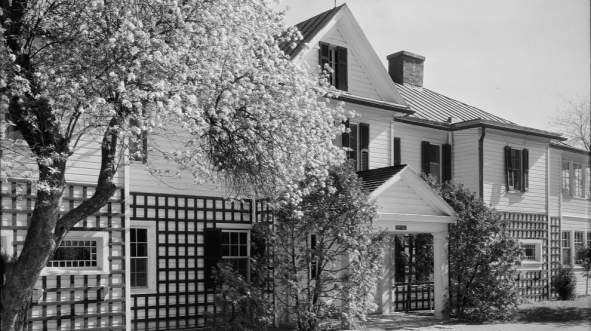 Exterior view of Foxcroft School in Middleburg, Virginia, featuring a historic white building with black shutters and springtime trees in bloom.