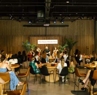Photo shows a group at a special event inside Assembly Hall with people seated at round tables from the back of the room, looking towards panelists seated on the stage.