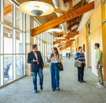 Men and women in professional attire gathering in pre-function space during a conference.