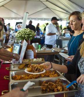 Visitors line up to enjoy the food being served community-style at an Outer Banks, NC Seafood Festival.