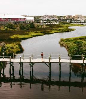 A woman walks across a wooden walkway at Hatteras Landing Marina.