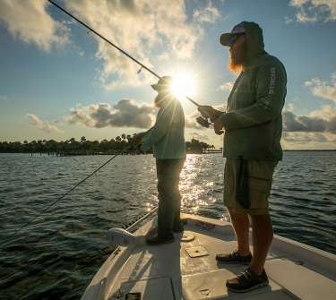 Two men fish from a boat as the sun rises over St. Joseph Bay