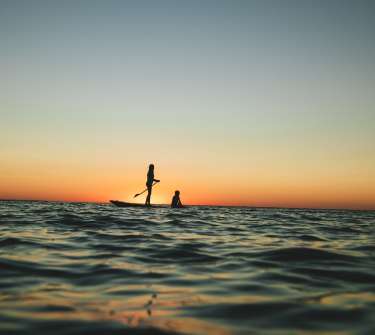 A young girl paddleboards at sunset on St. Joseph Bay