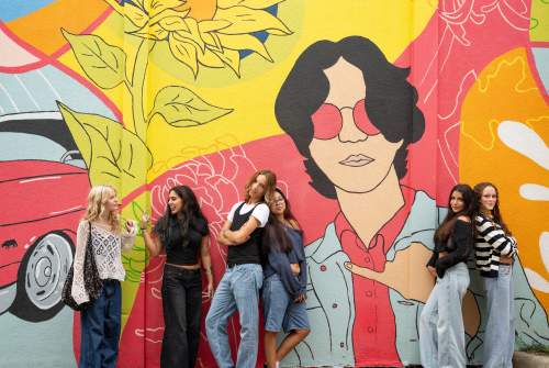 A group of young women standing in front of a mural in McKinney.