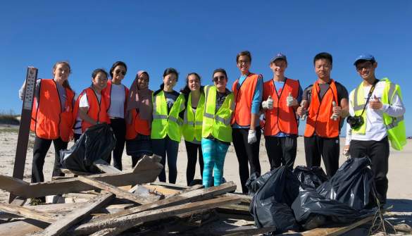 A beach clean-up crew in safety vests poses with the debris they collected on the OBX.