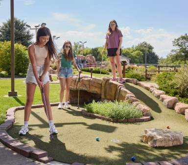 Three friends mini golfing at the Greeley Family FunPlex