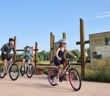 Family Biking outdoors on the Poudre River Trail with sign behind them