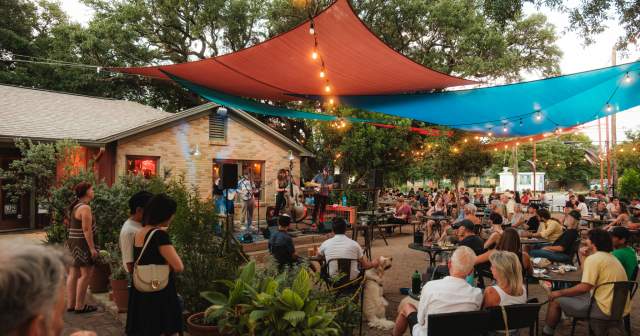 Photo of people sitting on at outdoor patio at Radio Coffee & Beer watching a live band performing on stage.