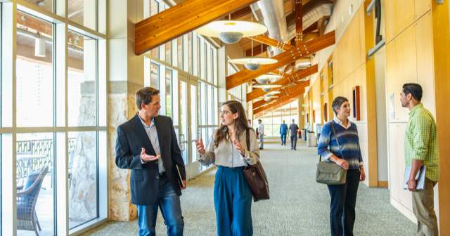 Men and women in professional attire gathering in pre-function space during a conference.