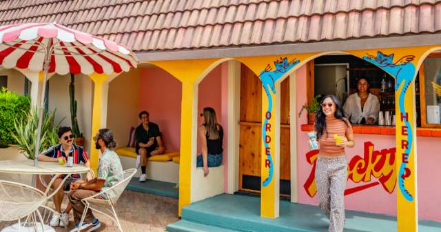 People sitting around an outdoor courtyard with a colorful bar.