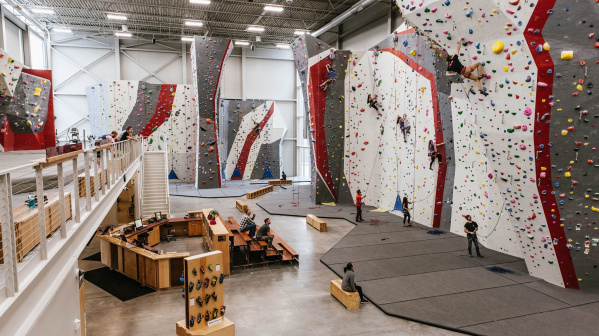 An interior shot showing many rock climbers climbing in Adventure Rock's indoor facility