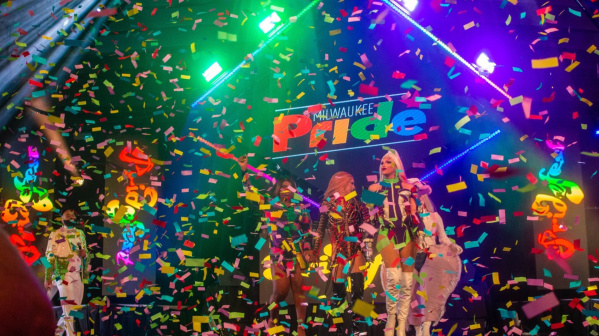 A group of drag queens performing onstage at Pridefest in Milwaukee as party streamers fall around them