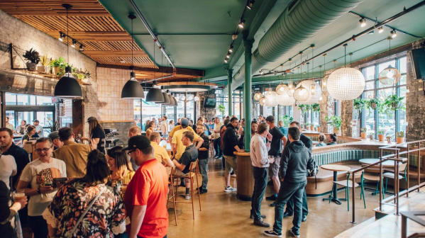 A group of diners talking and eating inside of the Triple Taproom & Kitchen on Milwaukee's East Side