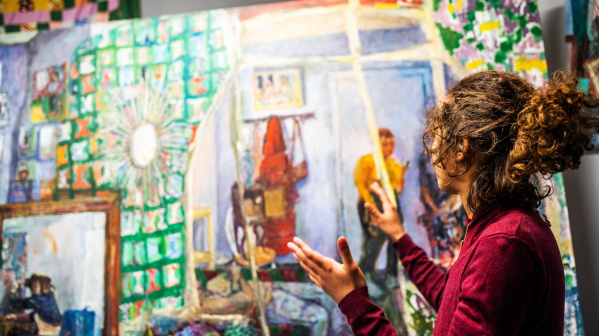 artist talking with art in background