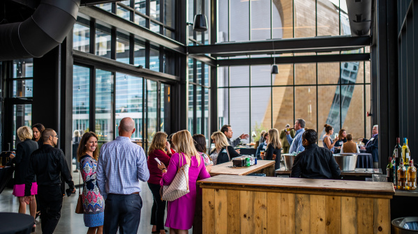 Group of meeting attendees mingling at Gather with Fiserv Forum out the window