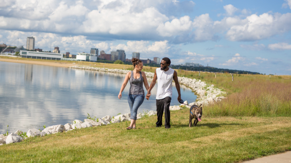 Couple waling a dog along the shores of Lakeshore State Park