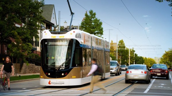 street car on road, cars and pedestrians passing