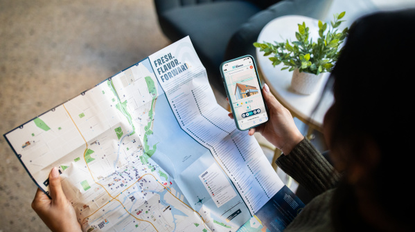 A person holding an official visitors map of Milwaukee with a Map King App open.