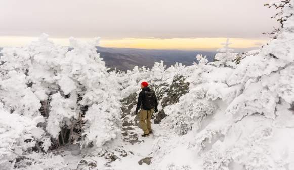 hiker on the top of Mt. Mansfield with snowy trees and icy landscape.